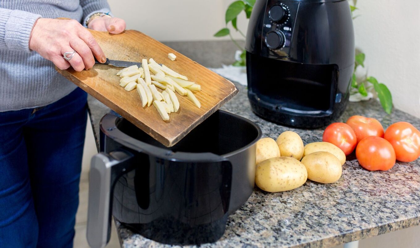 woman putting potatoes in air fryer